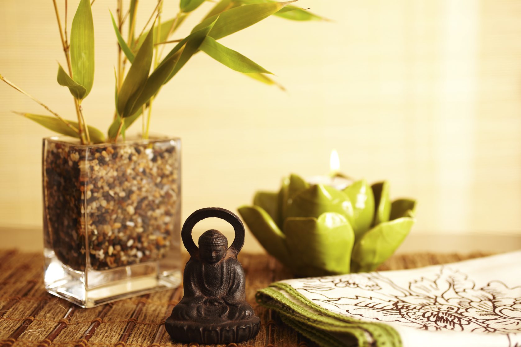 Statuette de bouddha à côté d'un vase Bouddha en décoration avec un vase, une bougie et une plante dans un style zen.